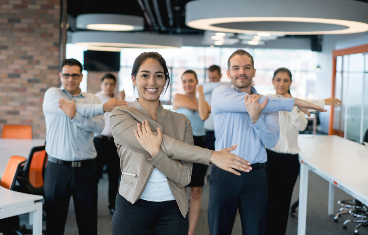 Business people stretching at the office - Happy group of business people stretching while taking a break from work at the office wellbeing concepts.